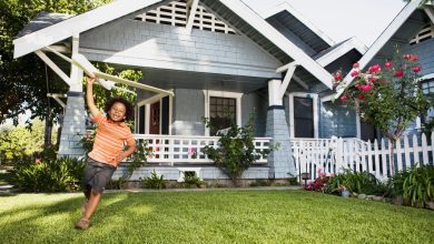 Boy with toy airplane in front yard of house